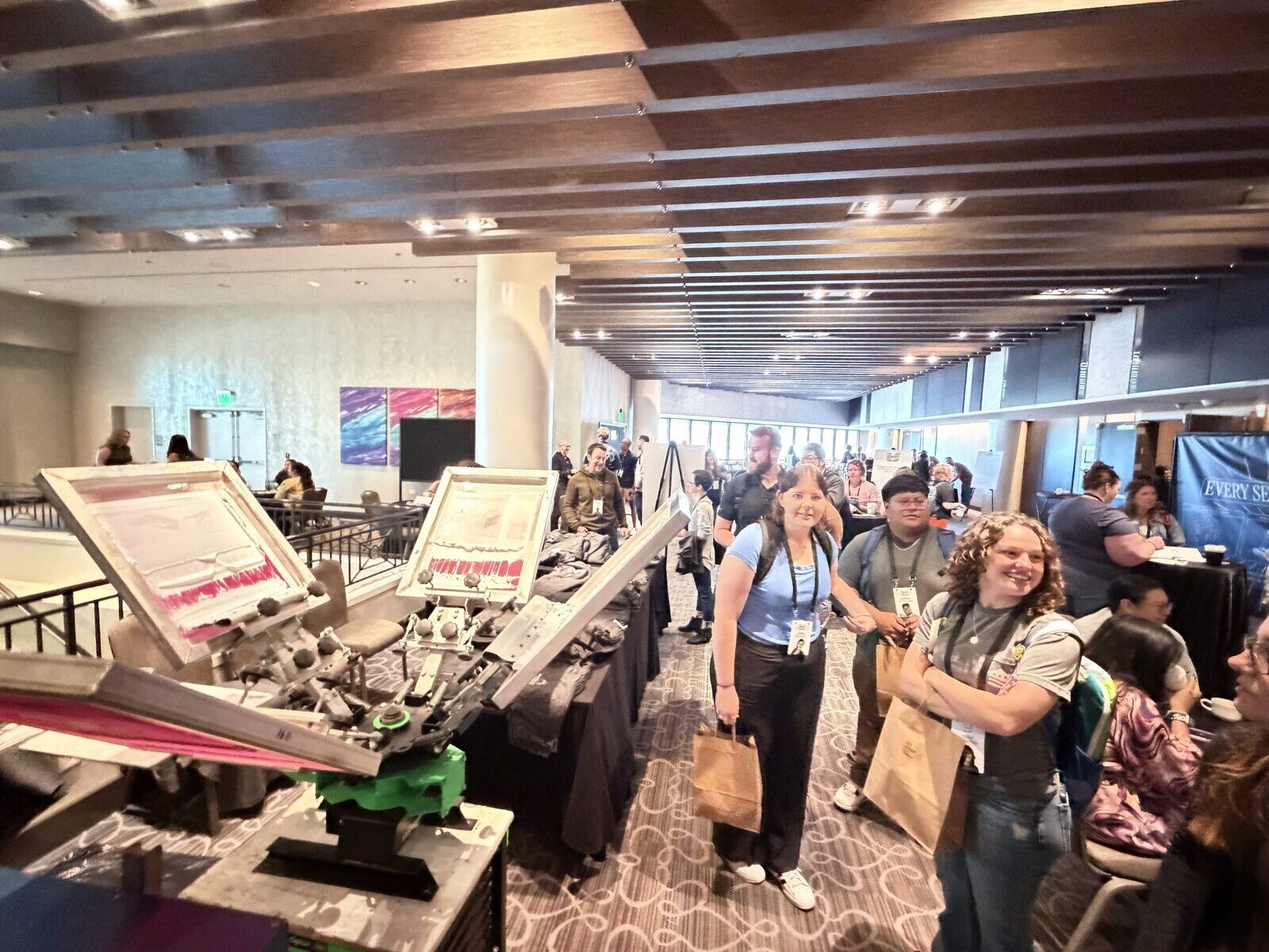 Smiling guests collecting freshly printed items at an event print station